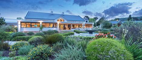 A modern house with a large garden, a fountain, and a well-maintained lawn.