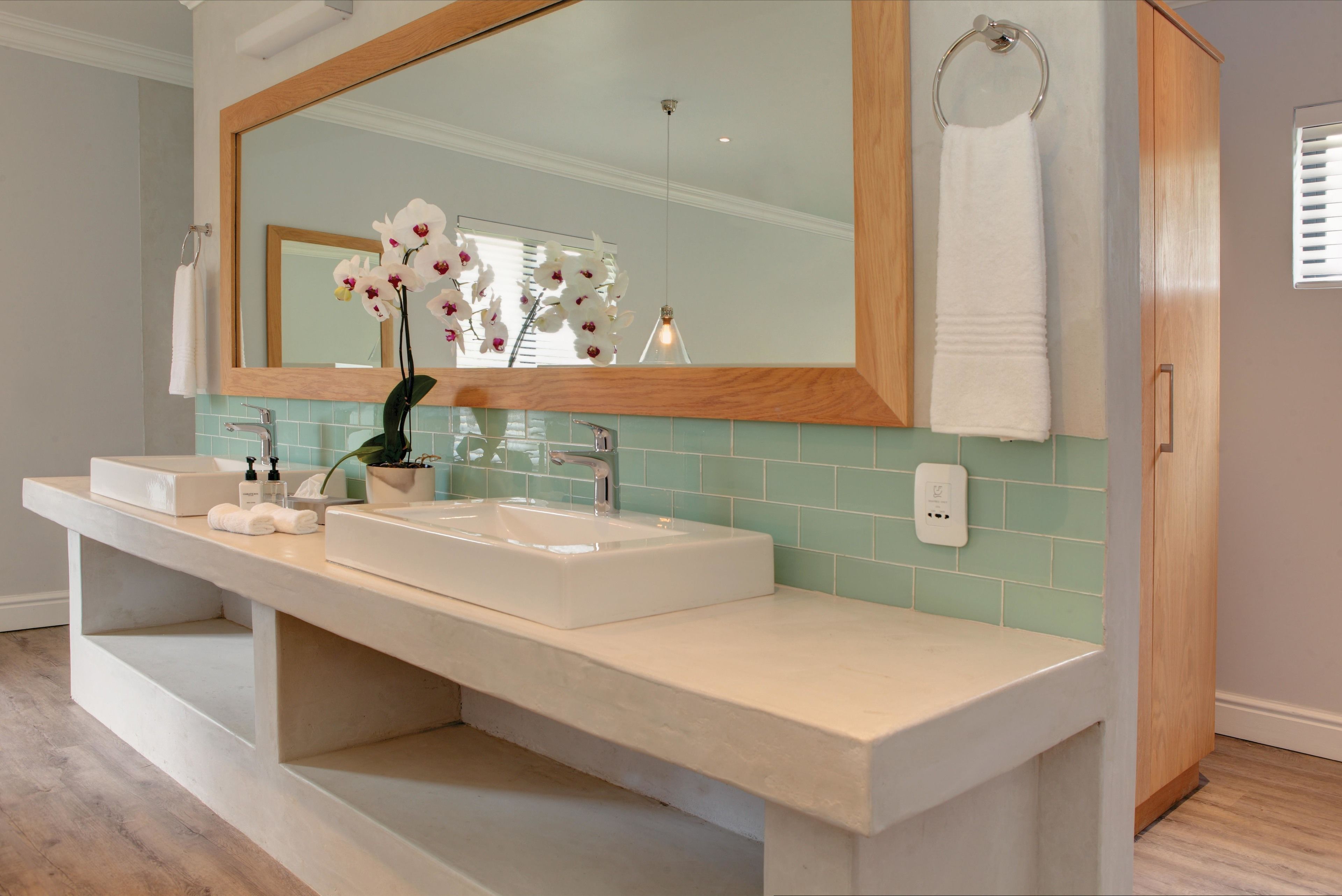 A bathroom with a double sink vanity, a large mirror, and a towel rack.