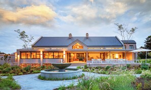 A modern two-story building with a large entrance, outdoor seating area, and a central water feature. - Knysna Hollow Country Estate (Knysna)
