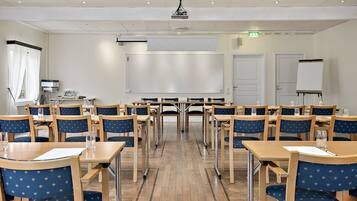 A conference room with tables and chairs, a projector, and a whiteboard.