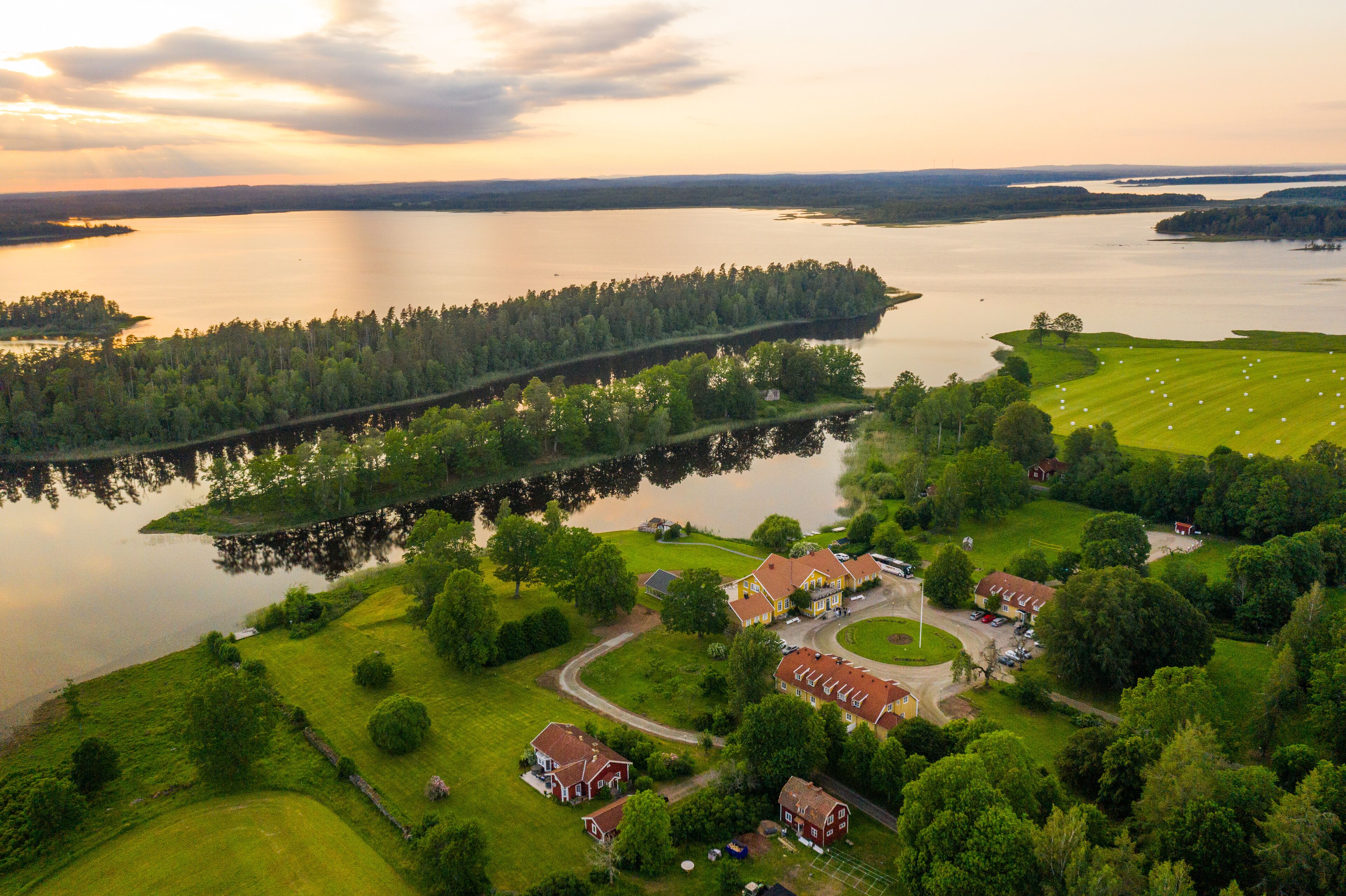 An aerial view of a lakeside property with a small cluster of houses, a golf course, and a dock.