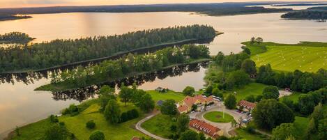 An aerial view of a lakeside property with a small cluster of houses, a golf course, and a dock.