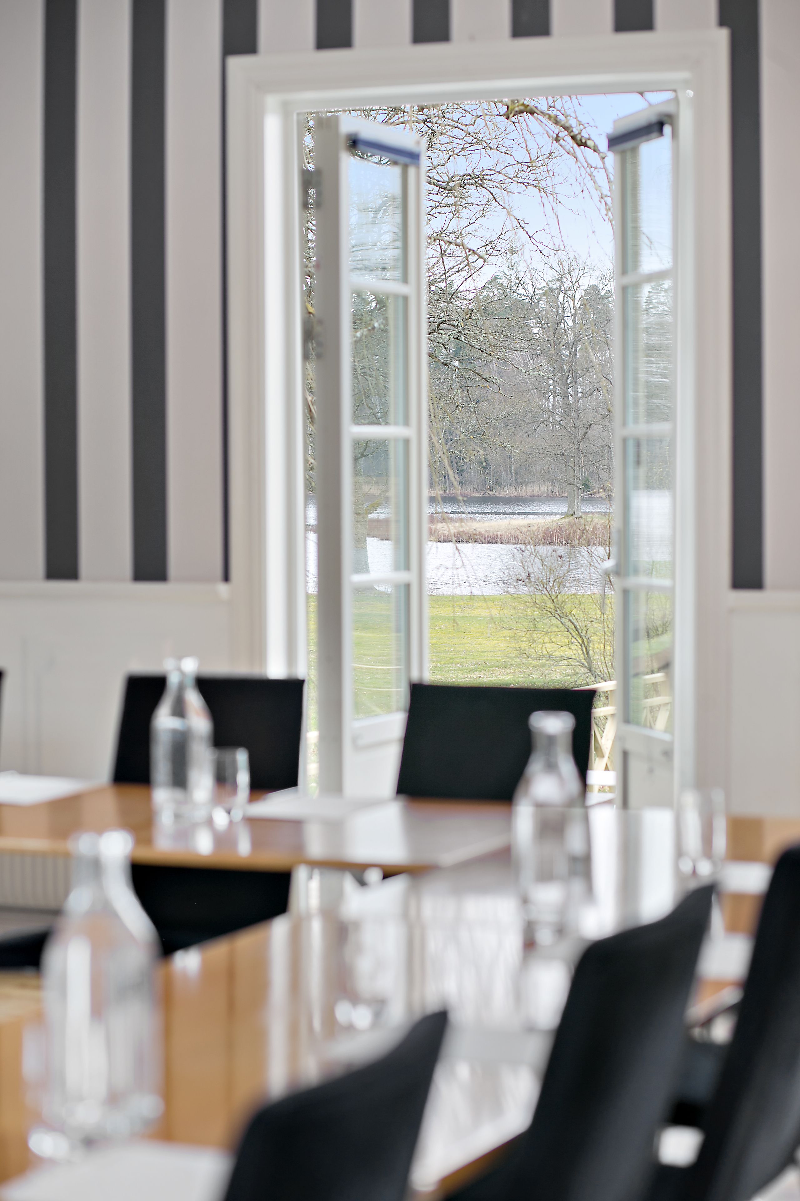 A conference room with a large table, chairs, and a view of a snowy landscape through a glass door.