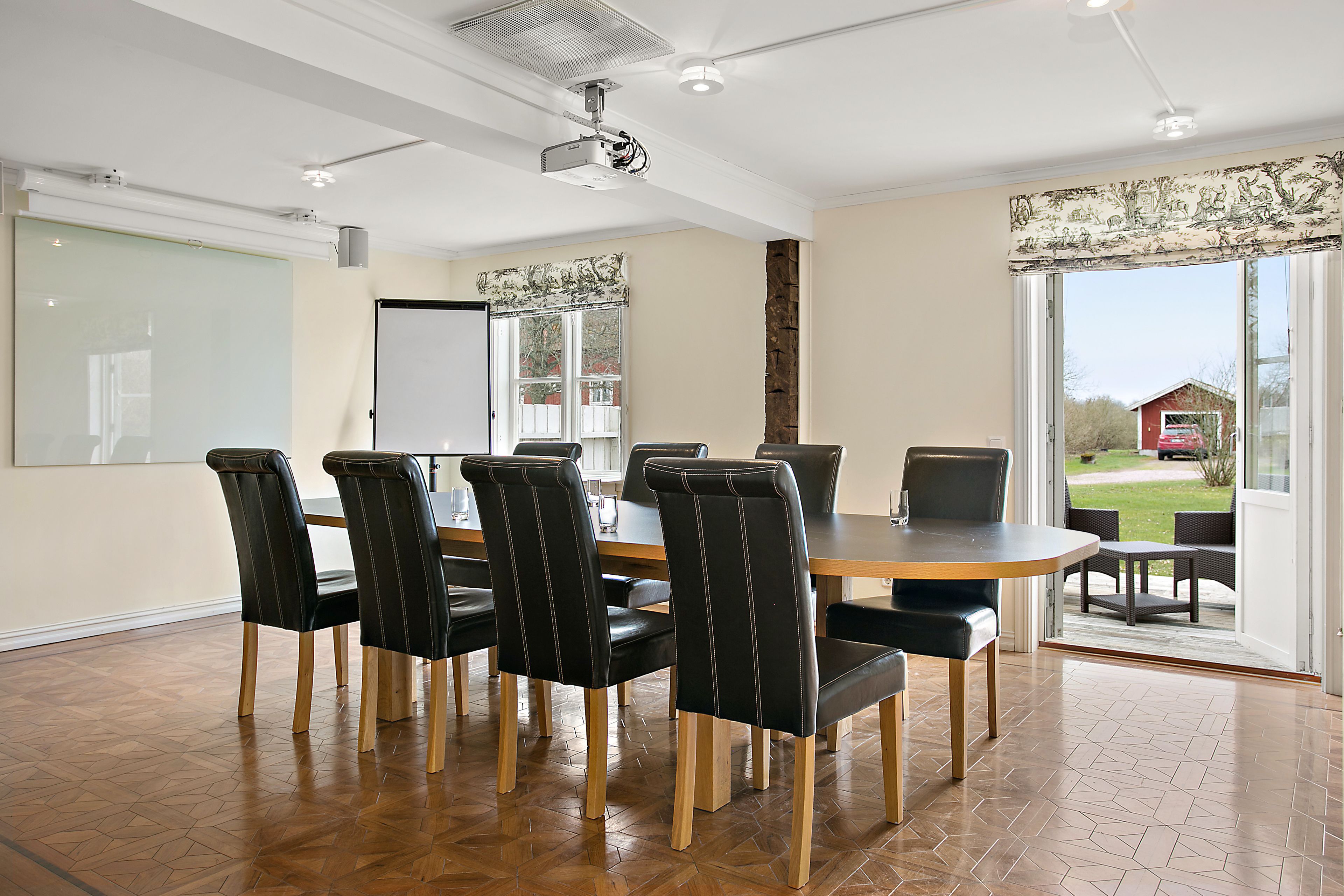 A conference room with a large table, six chairs, a projector, and a whiteboard.