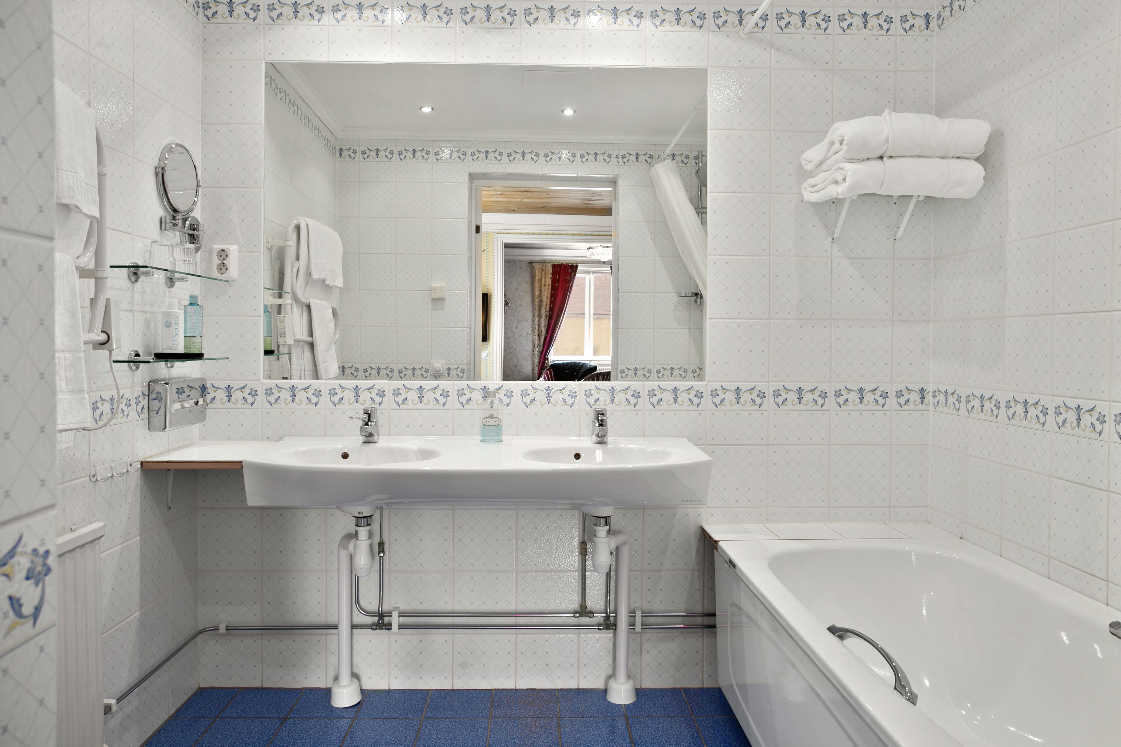 Un baño con un lavabo blanco, dos llaves, un espejo y una bañera.