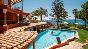 A pool area with a clear view of the ocean, surrounded by palm trees and lounge chairs. -  Boutique Hotel Vivenda Miranda (Lagos)