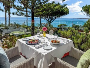 Un área de comedor al aire libre con una mesa preparada para dos, con vista al mar.