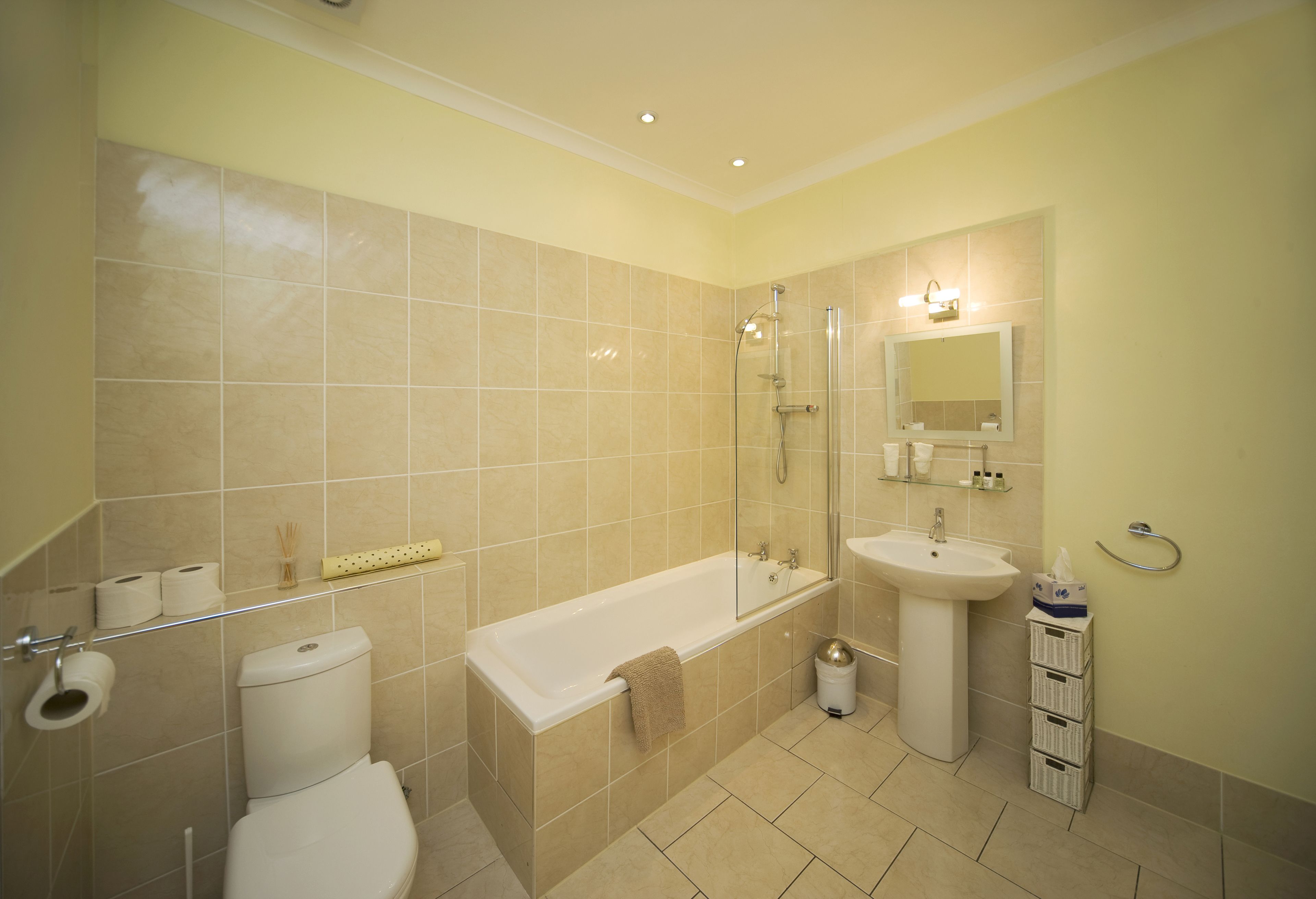 A bathroom with a bathtub, toilet, sink, and a glass shower enclosure.