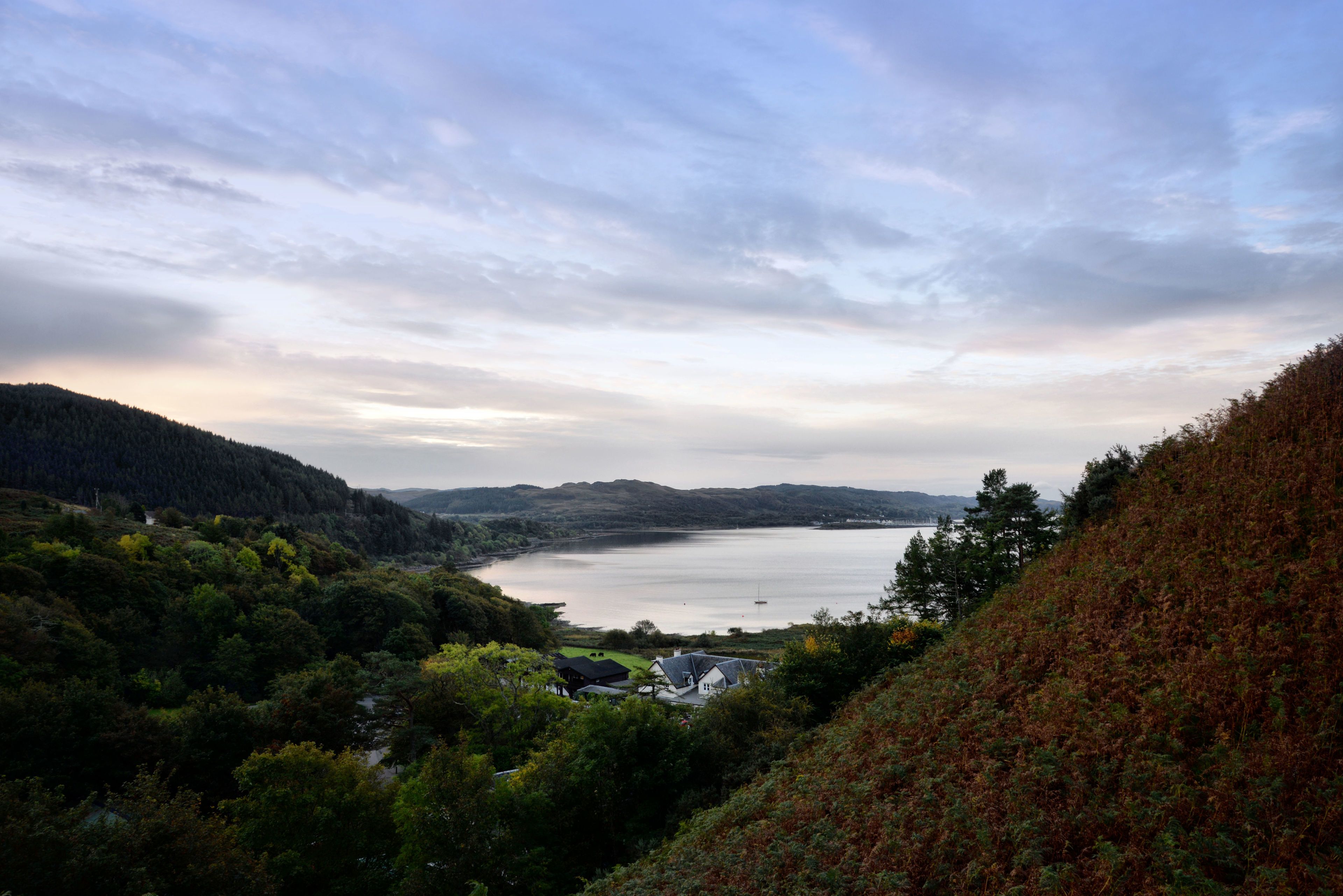 Una vista panorámica de un lago rodeado de colinas y un bosque denso.