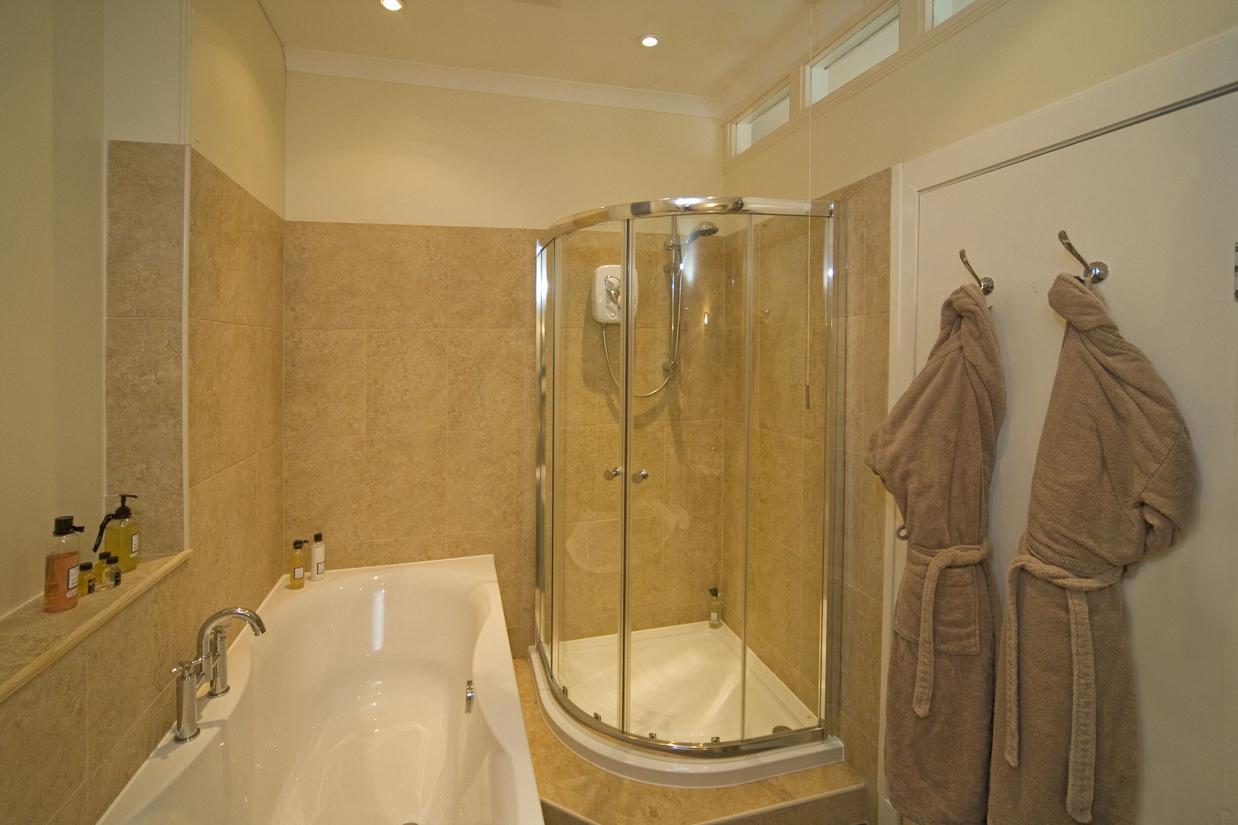 A modern bathroom with a glass-enclosed shower, a freestanding bathtub, and two towels hanging on the wall.