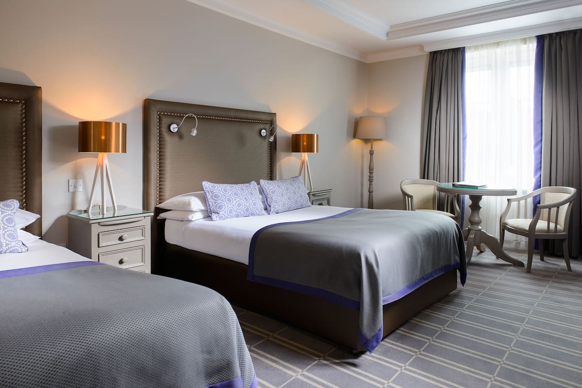 A hotel room with two beds, a desk, and a chair.
