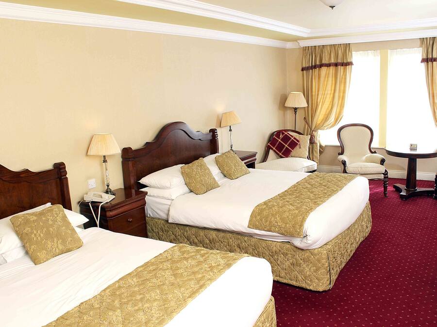 Habitació d'hotel amb dos llits grans, un escriptori, una cadira i una taula petita.