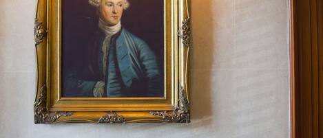 A portrait framed in an ornate gold frame on a wall.