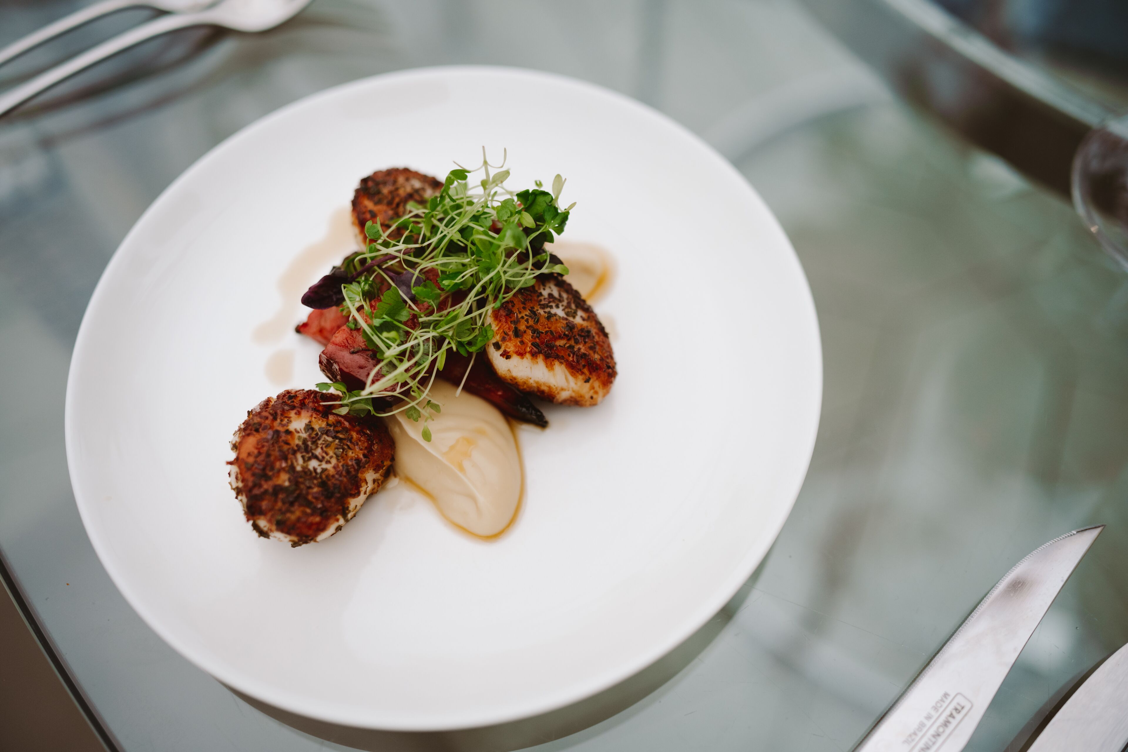 A white plate with food on a glass table.