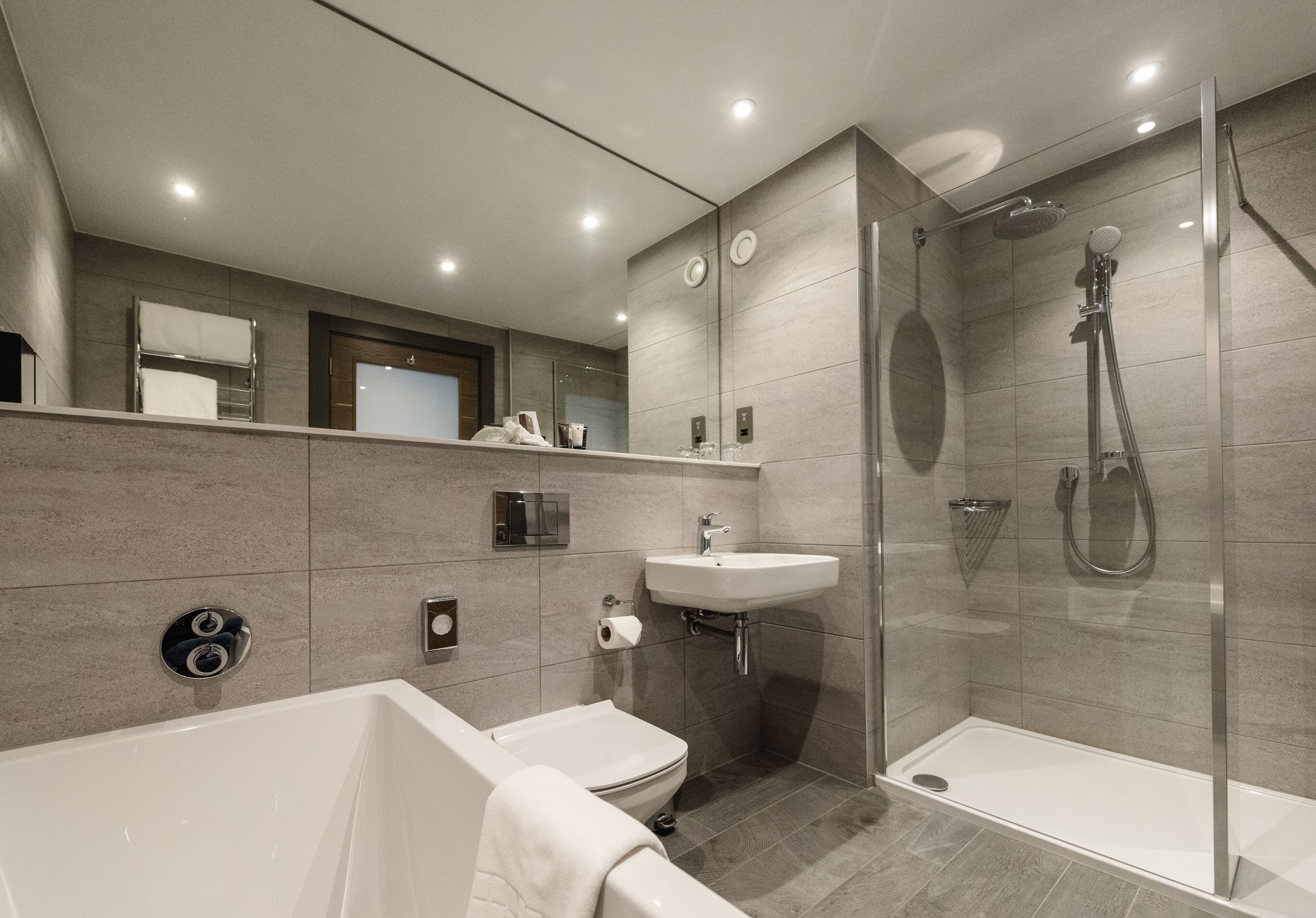 Een moderne badkamer met een bad, toilet, wastafel en een inloopdouche.