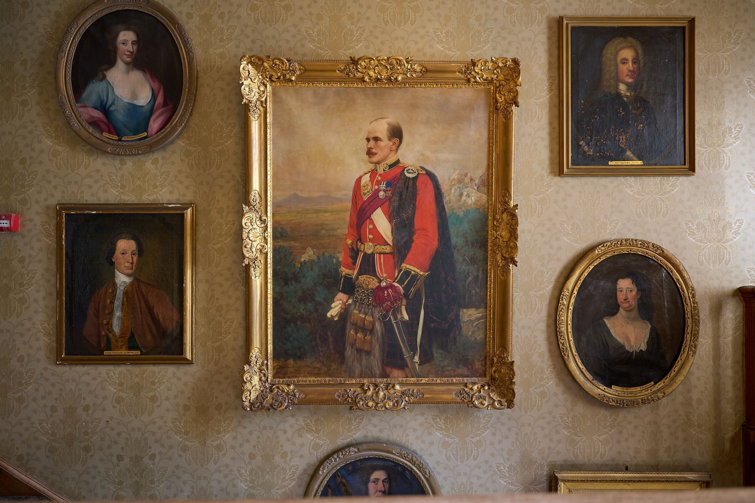 Een muur met meerdere ingelijste portretten van historische figuren.