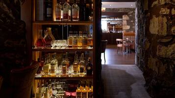 Een bar met flessen drank en glazen op de planken.