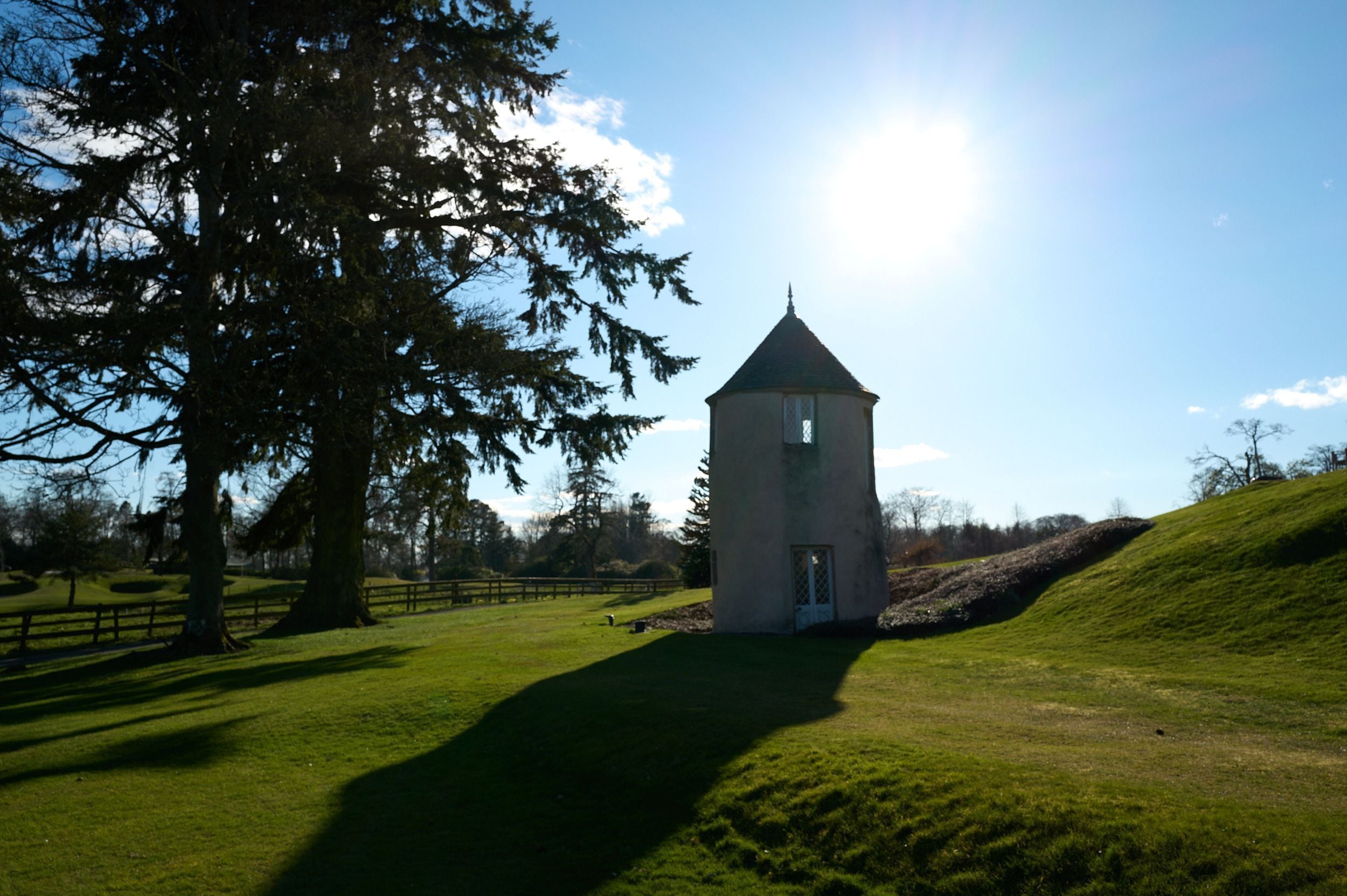 A tower structure in a grassy field with a clear sky.
