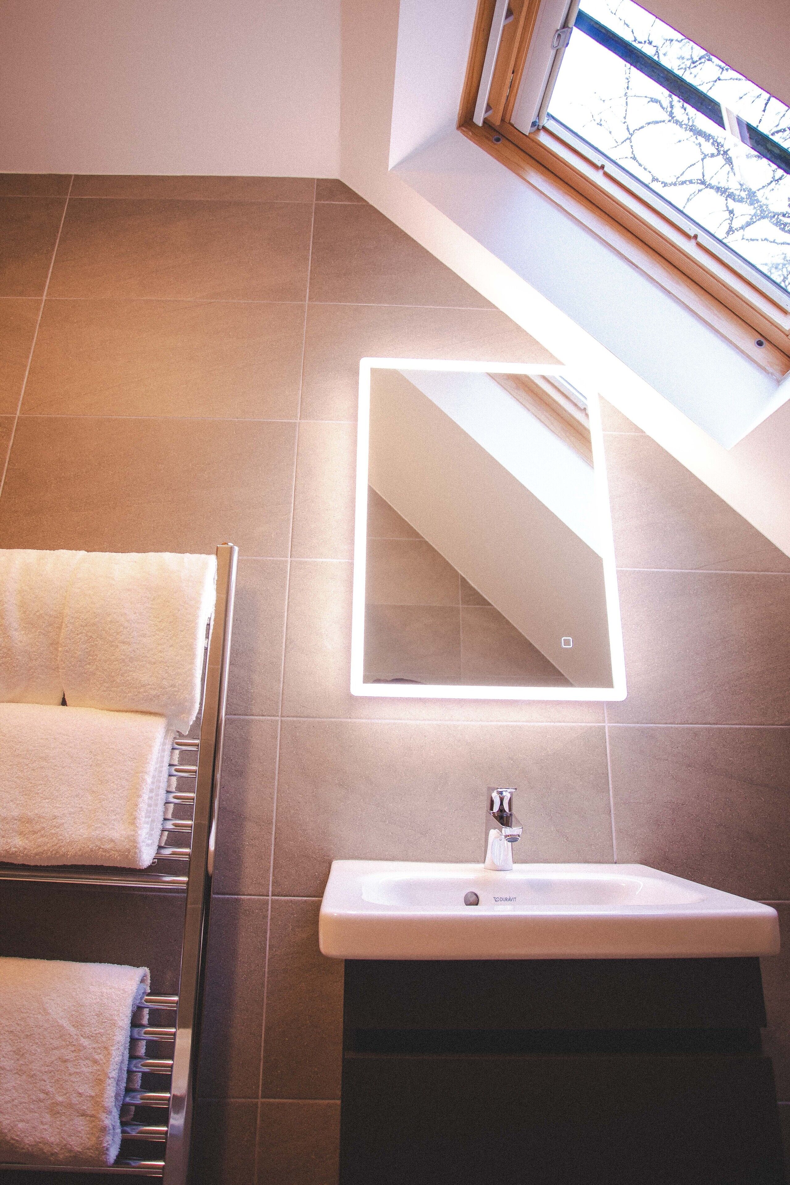 A bathroom with a skylight, a mirror, and a sink.