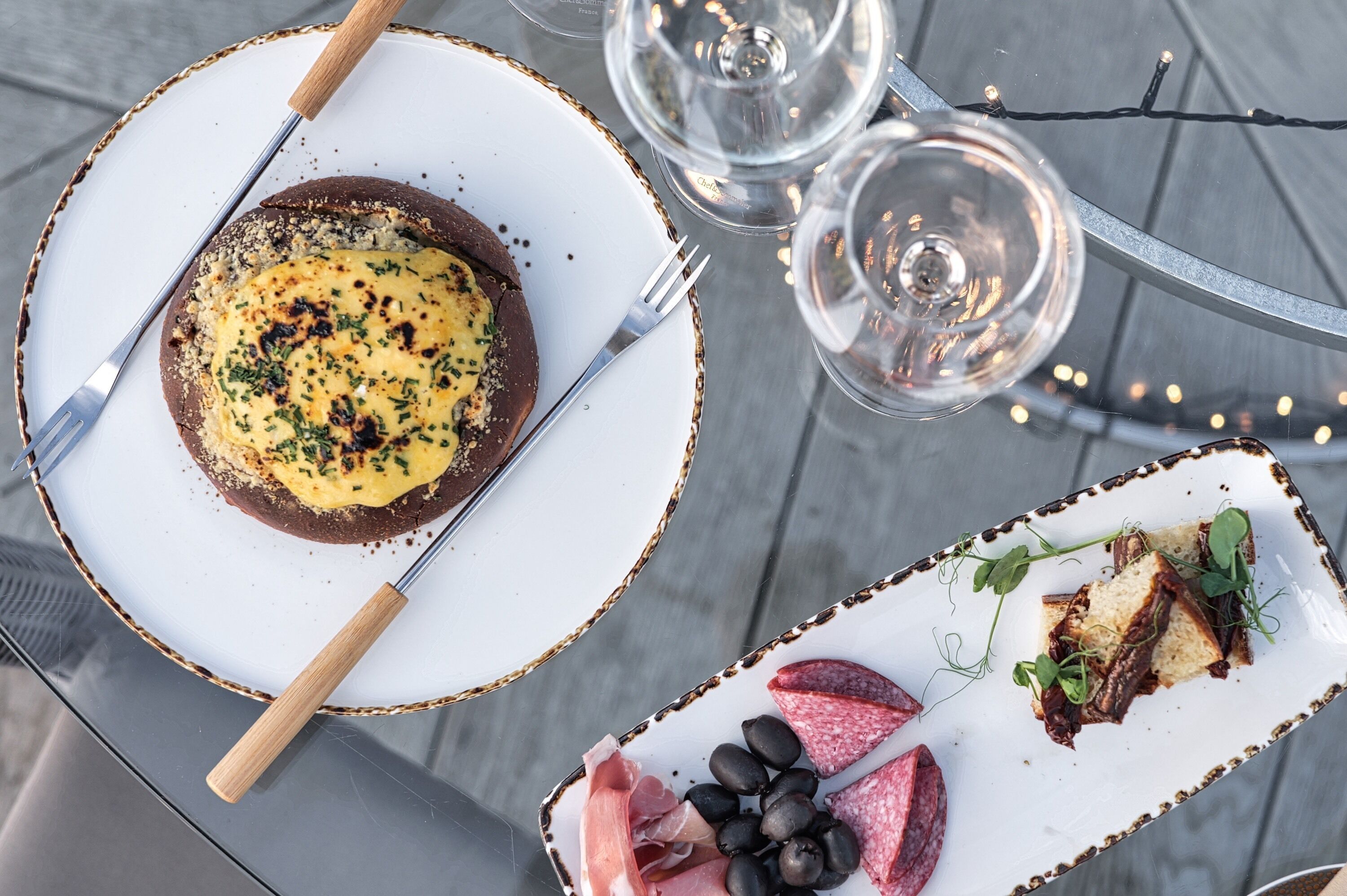 A dining table with a plate of food, a glass of wine, and a glass of water.