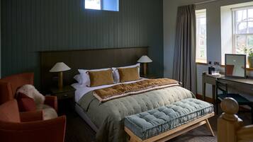 Ein Schlafzimmer mit Bett, Nachttischlampen, Schreibtisch, Stuhl und einem Fenster mit Vorhängen.