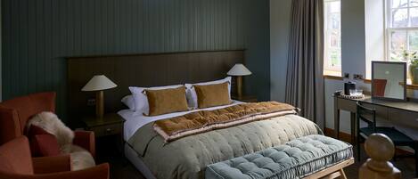 A bedroom with a bed, bedside lamps, a desk, a chair, and a window with curtains.