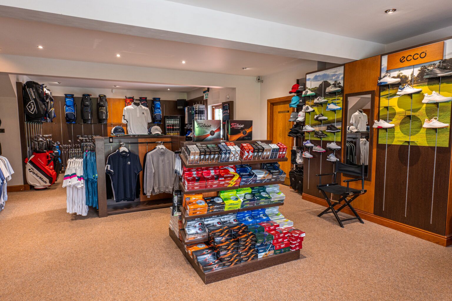 A golf store with neatly arranged golf bags, apparel, and accessories.