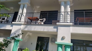 A multi-story building with balconies, white columns, and a mix of windows and doors.