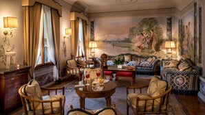 Una habitación lujosa con un cuadro grande, asientos cómodos y decoración elegante.