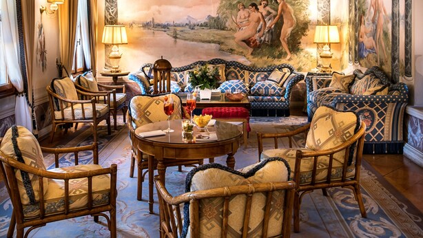 Una habitación lujosa con un gran mural, muebles elegantes y una araña.