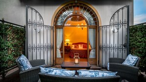 Una habitación de hotel con una cama, una mesa con una vela y muebles de mimbre.