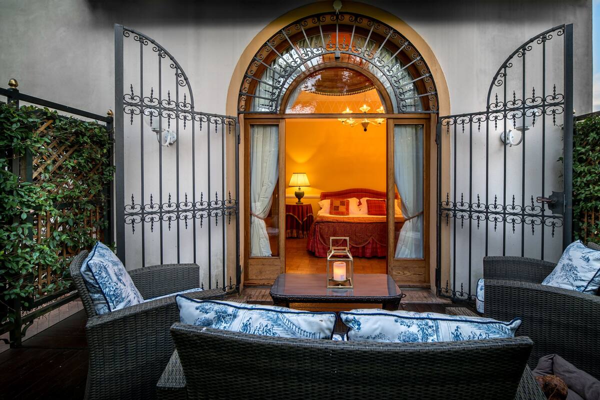 Una habitación de hotel con una cama, una mesa con una vela y muebles de mimbre.