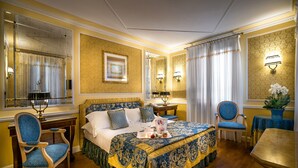 Un dormitorio espacioso con una cama grande, un rincón de estar con una mesa y sillas, y un espejo.
