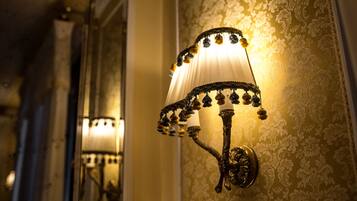 A wall-mounted light fixture with a decorative design, positioned against a wallpapered wall.