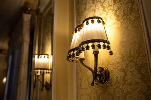 Un luminaire mural au design décoratif, fixé sur un mur recouvert de papier peint.