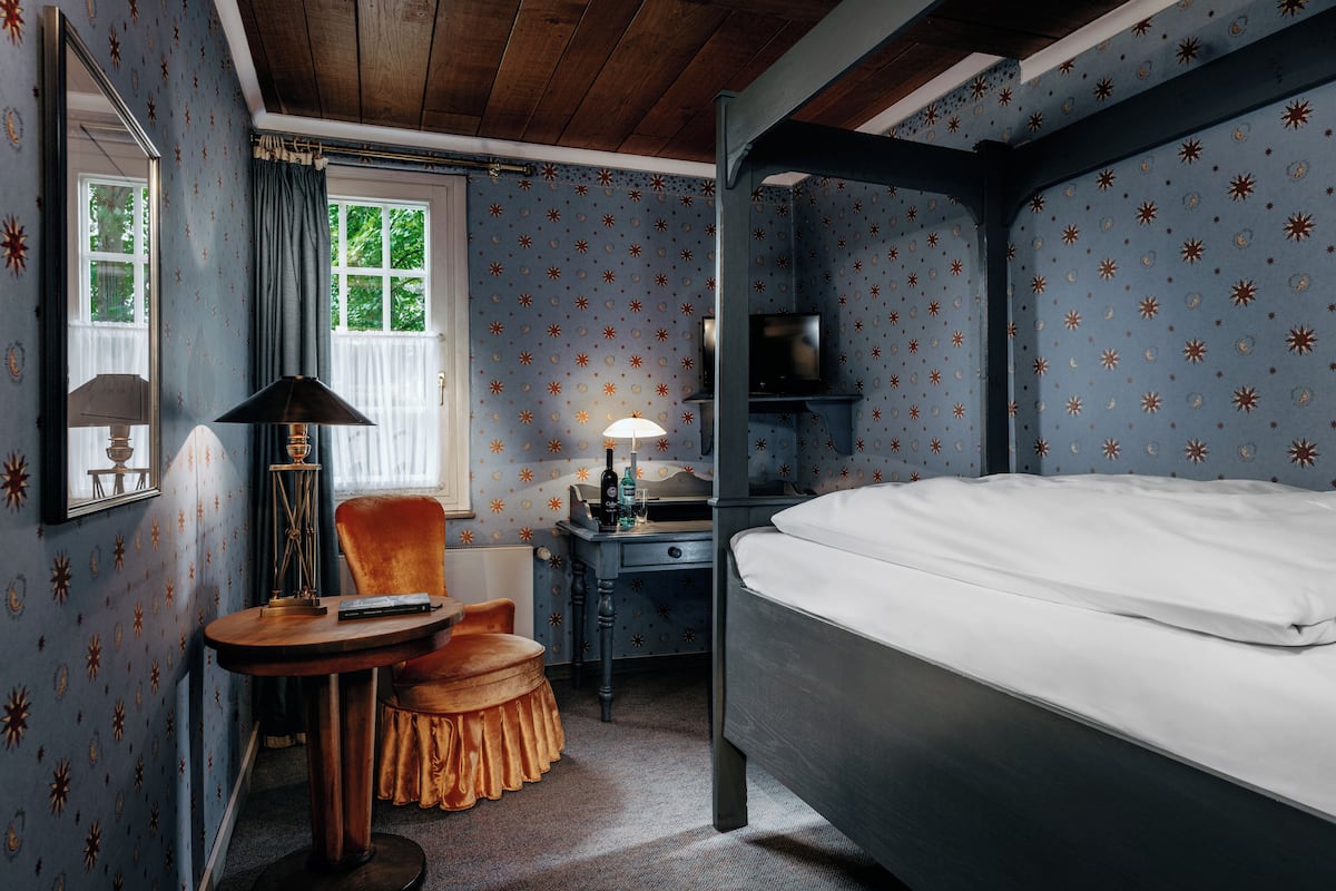 Une chambre avec un lit superposé, un bureau avec une lampe, une chaise et un miroir.