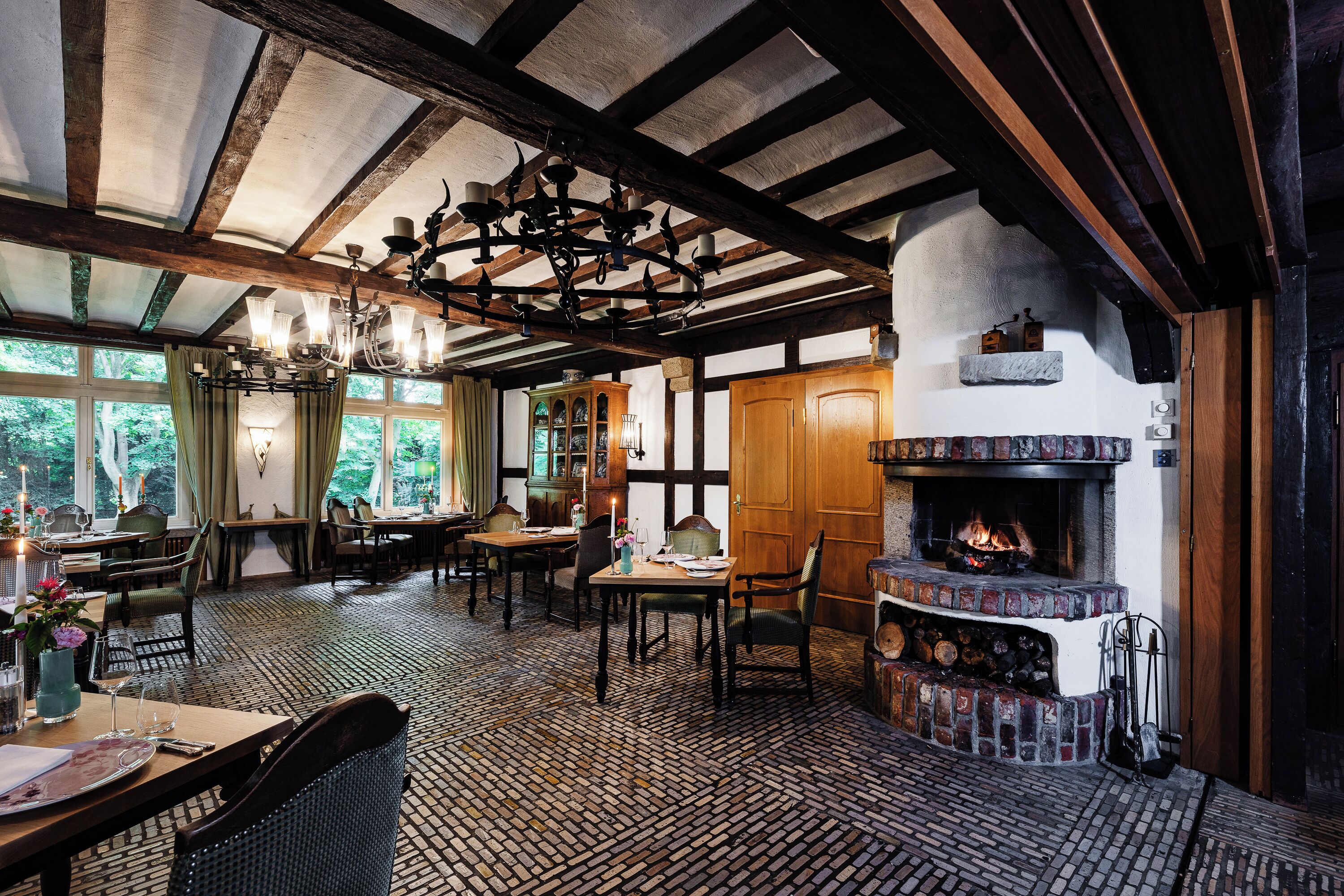 A traditional inn with exposed wooden beams, a fireplace, and a dining area with a patterned floor.