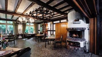 A traditional inn with exposed wooden beams, a fireplace, and a dining area with a patterned floor.