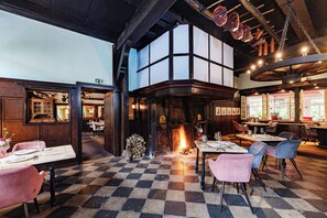 Ein Restaurant mit Schachbrettboden, Holzmöbeln und einem Kamin.