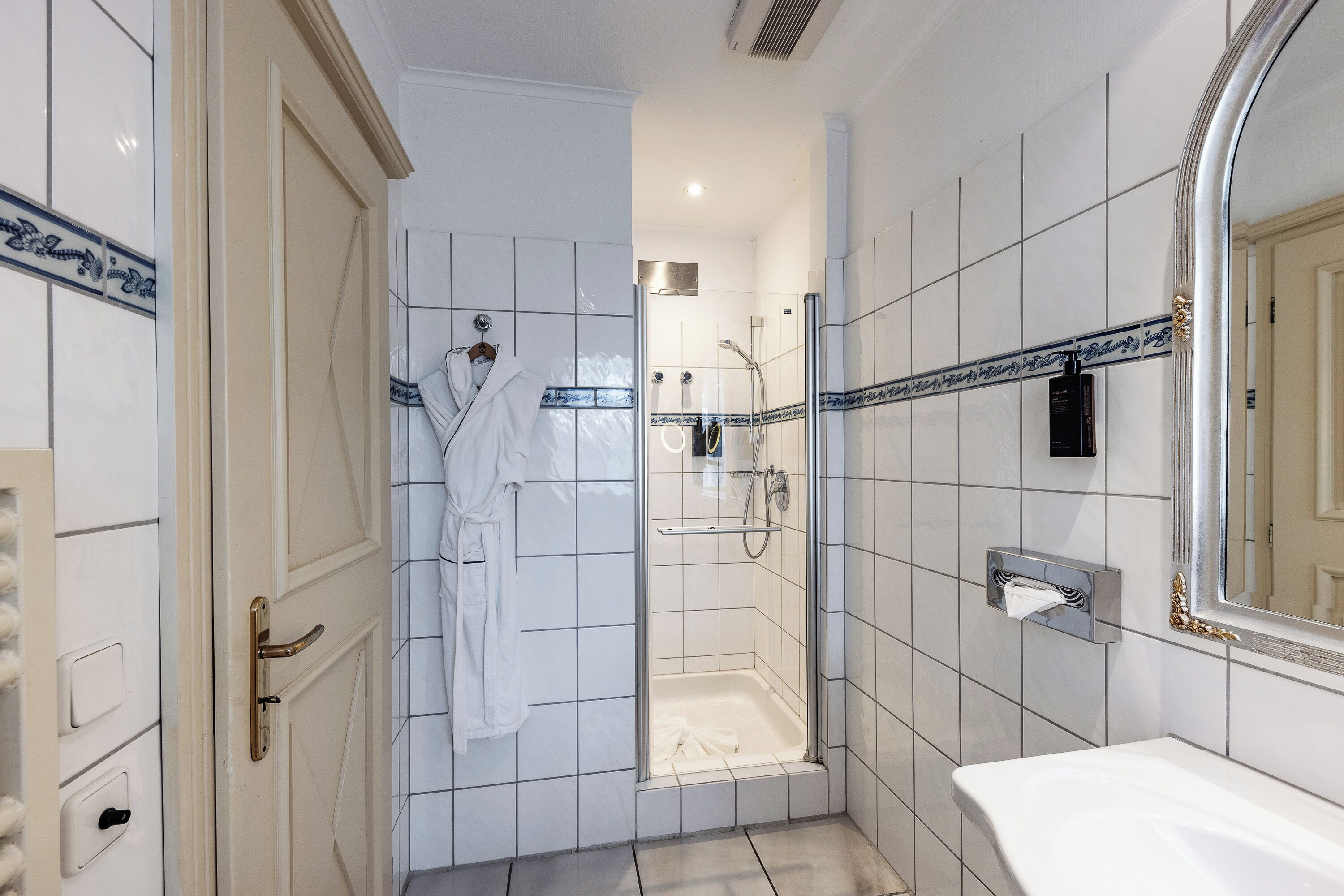 Un baño con ducha, bañera y un espejo grande.