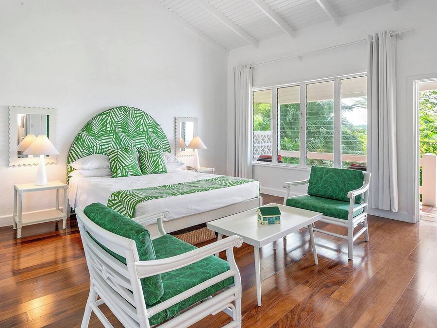 A room with a bed, two nightstands, a table, two chairs, and a window with curtains.