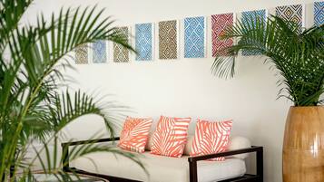 A sofa with patterned cushions, a wall with decorative panels, and a large potted plant.
