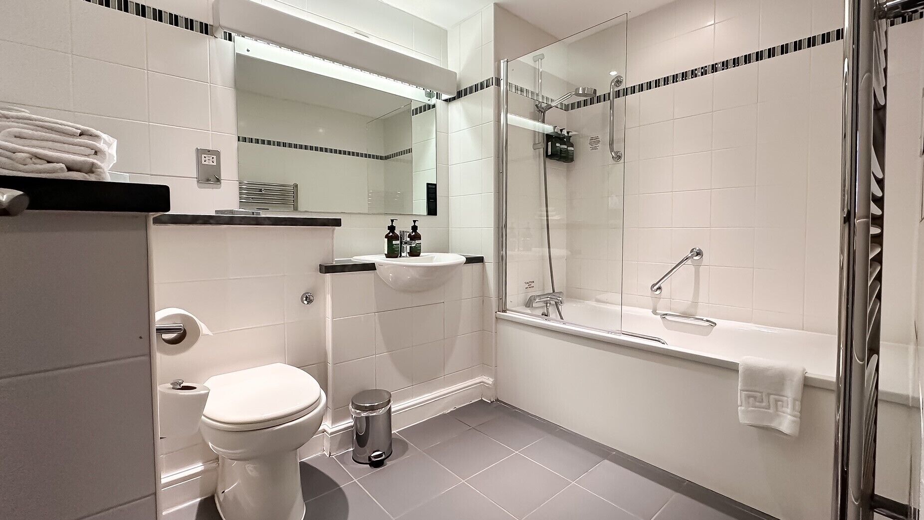 A modern bathroom with a toilet, sink, and glass-enclosed shower.