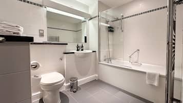 A modern bathroom with a toilet, sink, and glass-enclosed shower.