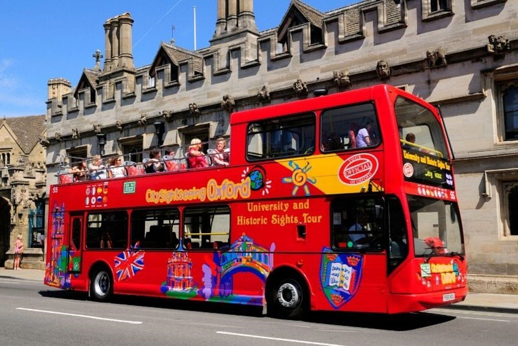 Ein roter Doppeldeckerbus mit der Aufschrift "CitySightseeing Oxford" und "Tour zu Universität und historischen Sehenswürdigkeiten" an der Seite.