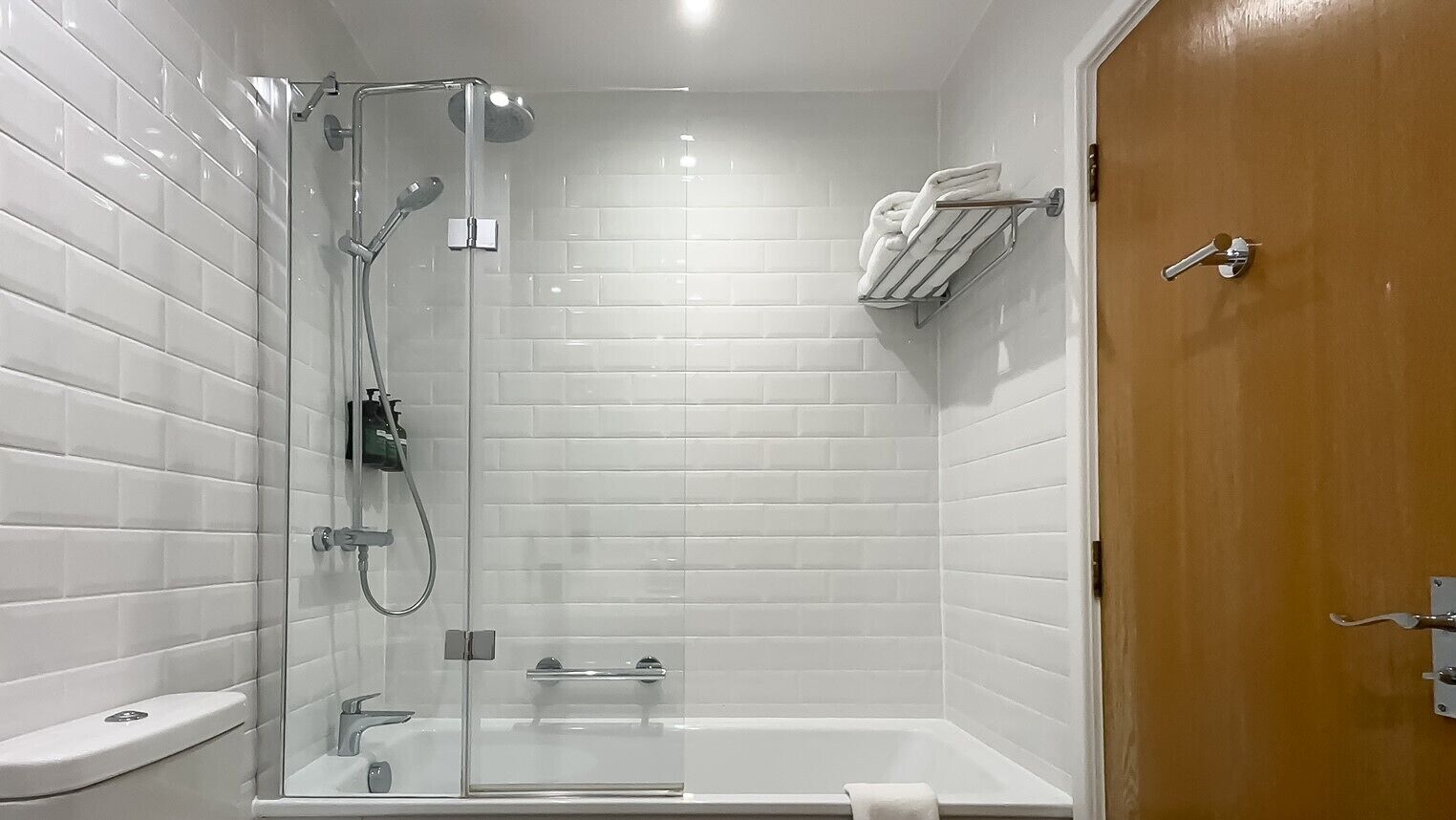 Une salle de bain moderne avec une douche à parois de verre, une baignoire blanche et une porte en bois.