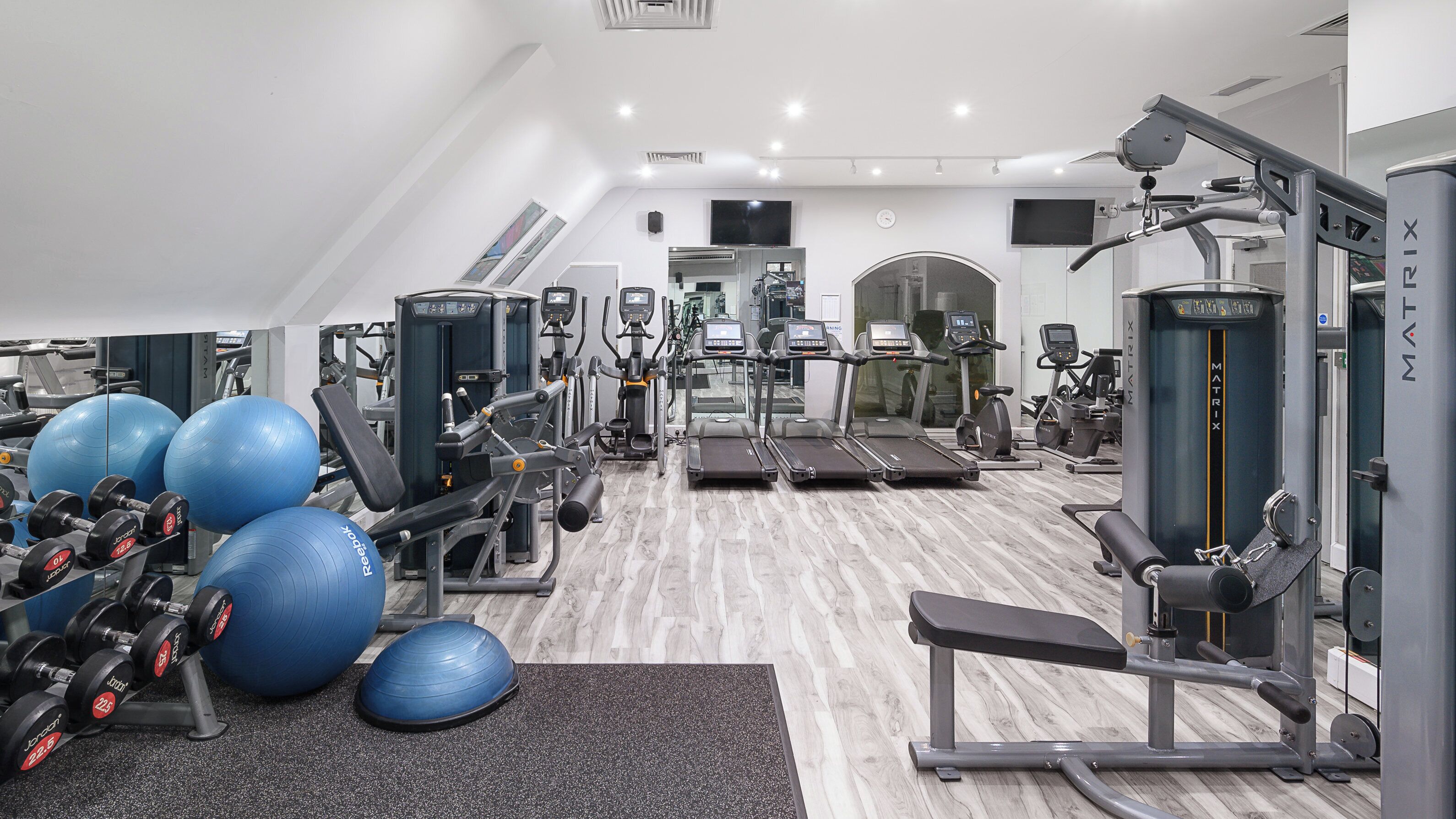 A gym with treadmills, weight machines, and exercise balls.