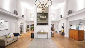 A spacious interior with a grand chandelier, a wooden reception desk, and a cozy seating area. - voco Oxford Spires by IHG (Oxford)