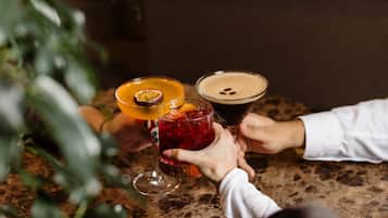 A close-up of three drinks on a table, with hands holding them.