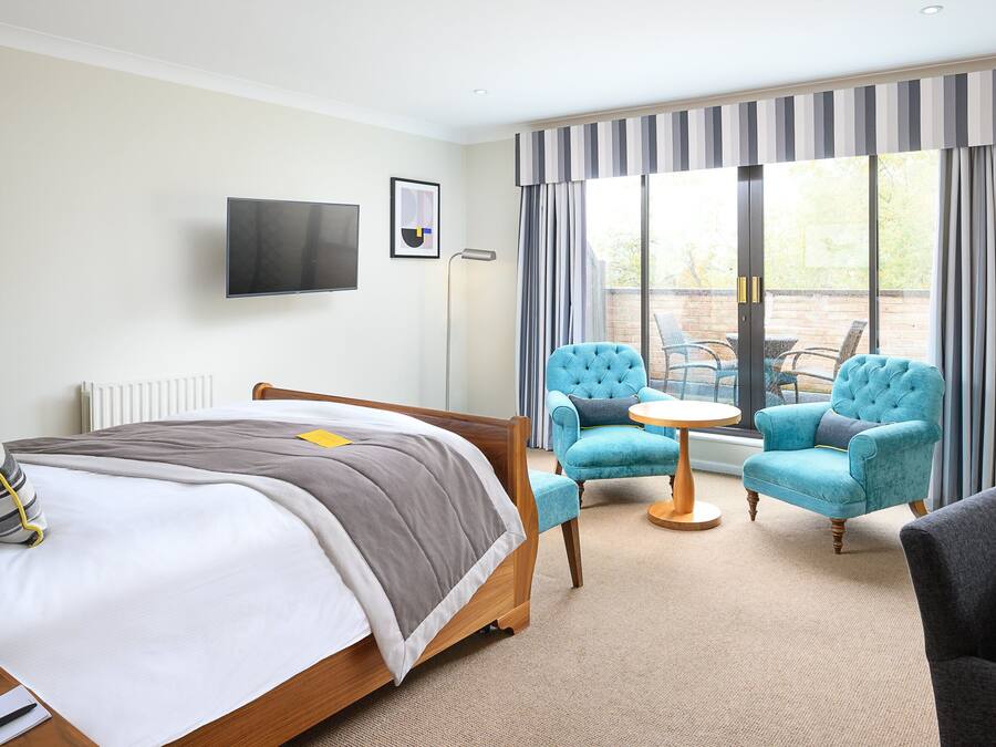 A hotel room with a bed, a desk, a chair, a TV, and a view of the outdoors.